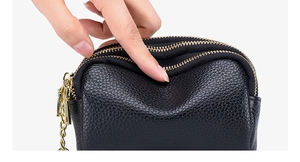 Detail of soft black pebble grain leather mini coin purse with golden triple zippers