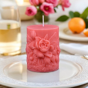Roze cilindrische geurkaars met rozenreliëf en gedetailleerde florale patronen