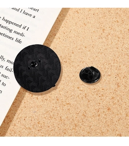 Nahaufnahme eines schwarzen Emaille-Pin-Rückens mit Wabenstruktur auf Korkgrund
