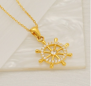 Close-up of golden ship wheel pendant necklace with sparkling cubic zirconia on white silk