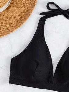 Detailed close-up of a black halter bikini top with striped texture on a marble surface