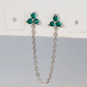 Macro detail of silver tassel chain earrings with three green cubic zirconia floral studs