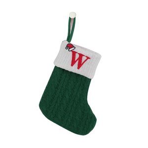 Detail of green knit Christmas stocking with white cuff and red embroidered letter W