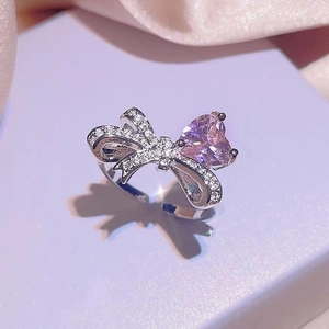 Adjustable silver bow ring featuring a pink heart stone and sparkling white crystals