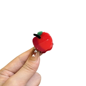 Cute red apple acetate hair clip with green leaf detail shown on white background