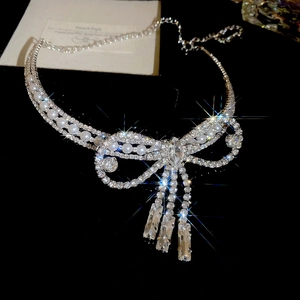 Close-up of sparkling bow necklace with hanging pearls and rhinestones on black background