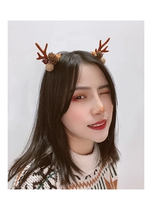 Detail of Christmas reindeer antler hair clips with pine cones and red berries on a model