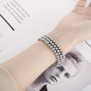 Detail of silver triple-layered elastic bead bracelet with highly polished metallic finish