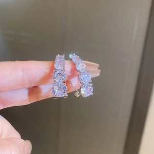 Close-up of silver-plated C-shaped earrings with micro-paved sparkling cubic zirconia stones