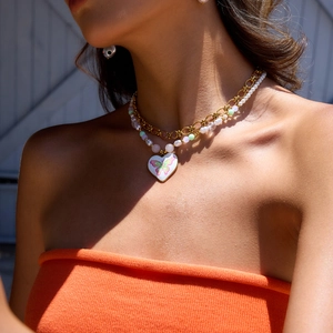 Détail d'un collier double couche en or 18 carats avec perle et pendentif cœur papillon