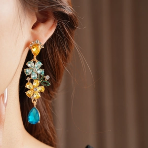 Detailed close-up of vintage gold earrings with multi-colored floral gemstones on a model