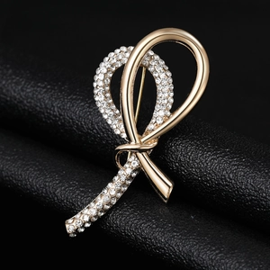 Detailed view of a gold ribbon brooch with sparkling crystals on black leather