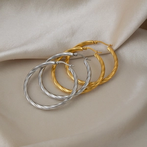 Chic twisted rope hoop earrings in gold and silver finish on elegant silk background