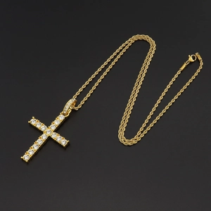 Macro shot of gold-plated tennis chain necklace with a sparkling cz cross pendant