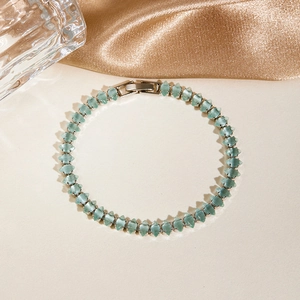 Macro shot of geometric cut light blue-green gemstones on a silver chain bracelet