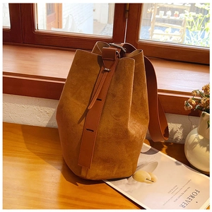 Detail of a brown suede bucket bag with smooth leather straps and silver metal hardware