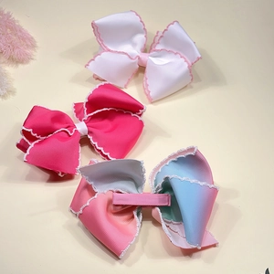 Détail de trois barrettes à cheveux en ruban gros-grain arc-en-ciel avec bords festonnés