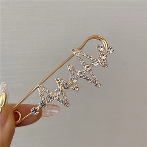 Macro detail of gold-plated safety pin brooch with sparkling rhinestones for waist adjustment