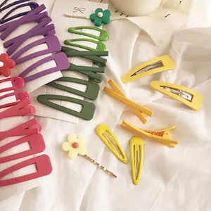 Buntes Haarspangen-Set in Avocadogrün und Lila mit Blumen auf weißem Stoffhintergrund