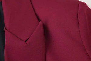 Dettaglio del rever rosso vino che mostra il tessuto intrecciato e le cuciture rifinite