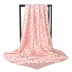 Pink satin square scarf featuring cherry and paisley prints hanging on a black metal frame