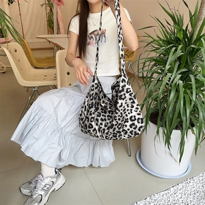 Leopard print canvas hobo bag showing large capacity on model in a cafe setting