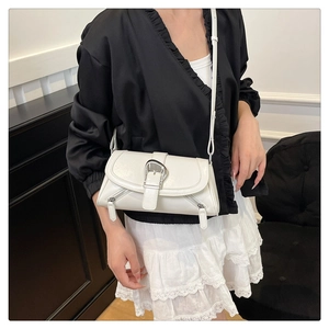 Close-up of a white Y2K style shoulder bag with large metal buckle and zipper detail