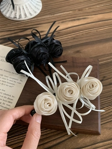Détail de pinces à cheveux rose en satin noir et crème avec des rubans élégants