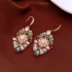 Macro view of vintage drop earrings with colorful zircon stones on dark silk fabric