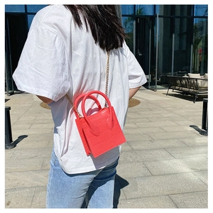 Outdoor shot of a red crocodile pattern crossbody bag with golden chain and twin handles