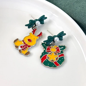 Close-up of Christmas reindeer and wreath stud earrings with pearl details and green bows