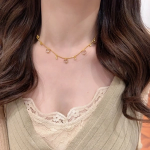 Close-up of elegant gold heart necklace with ice-clear teardrop tassels on female model