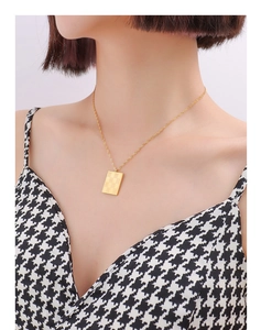 Close-up of golden checkerboard square pendant on a thin twist chain worn by a model