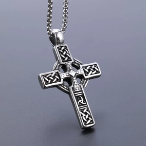 Macro shot of silver Viking cross pendant with intricate Celtic knot patterns and texture