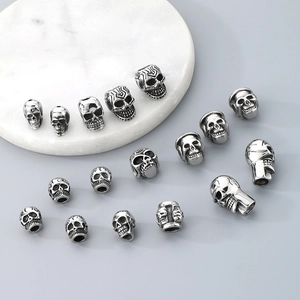 Macro detail of various vintage silver skull beads for DIY jewelry making on marble