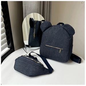 Detail of navy denim backpack with bear ears and matching waist bag set on white table