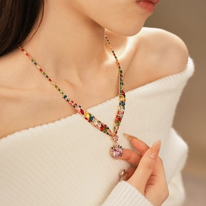 Detailed view of a gold-tone necklace featuring a sparkling pink heart-shaped zircon pendant