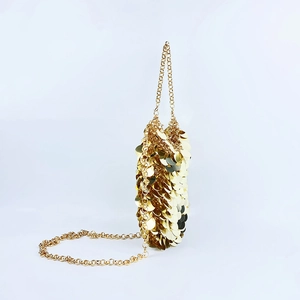 Detail of sparkling gold sequins and elegant fine metal chain on a compact crossbody bag