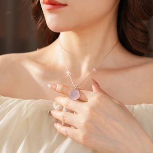 Close-up of rose gold chain with pink chalcedony Buddha pendant on a female model