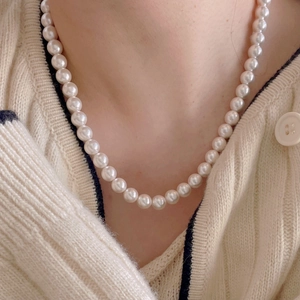 Close-up of elegant white pearl necklace on model neck with minimalist aesthetic