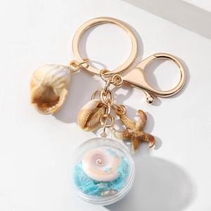 Detail van nautische sleutelhanger met zeester, schelpen en blauwe paillettenbol