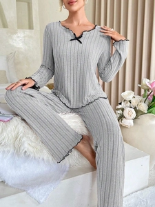 Close-up of light gray ribbed pajamas with black lettuce trim and decorative bow detail