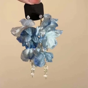 Detailed shot of silk texture blue flower earrings with gold chains and clear beads