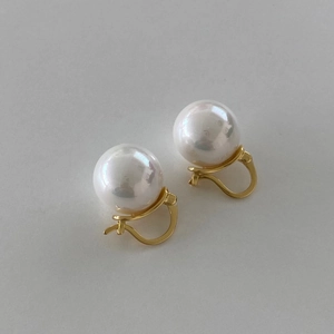 Detailed view of large white pearl earrings with golden minimalist clasp closure