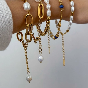 Gold layered bracelet set featuring pearls and blue beads on a female model wrist
