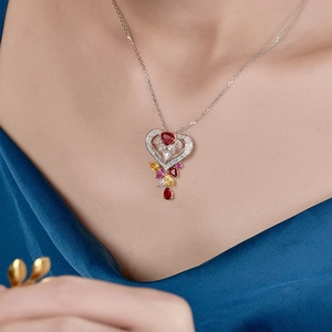 Elegant silver heart necklace with red and yellow gemstones worn by a female model