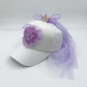 Dettaglio del cappello bianco con corona scintillante, fiocco viola e velo in tulle