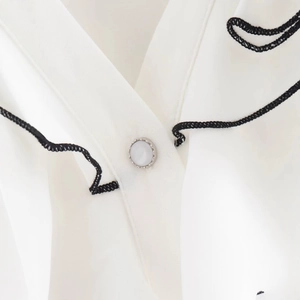 White casual blouse with layered ruffles, black wavy trim and decorative button detail