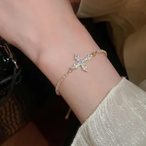 Luxuriöses goldenes Kreuzarmband mit Zirkon-Pavé-Kristallen am weiblichen Handgelenk