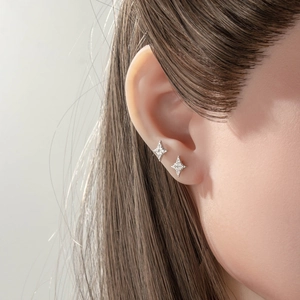 Minimalist silver star-shaped ear studs with cubic zirconia on model's ear